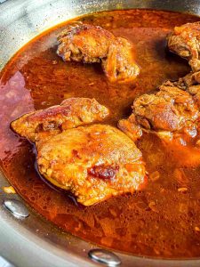 Side view of Creamy Coconut Milk Chicken Thighs in Skillet with Chicken Stock and sauce