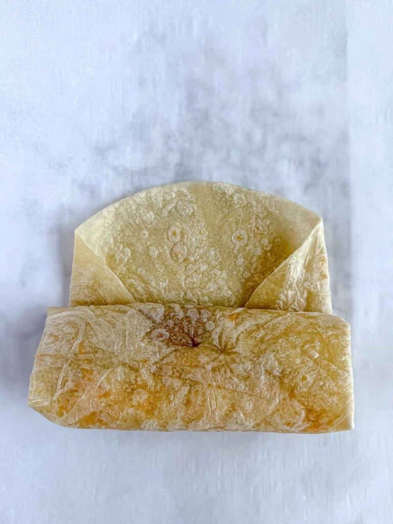 overhead view of forming bean and cheese burrito folded and rolled