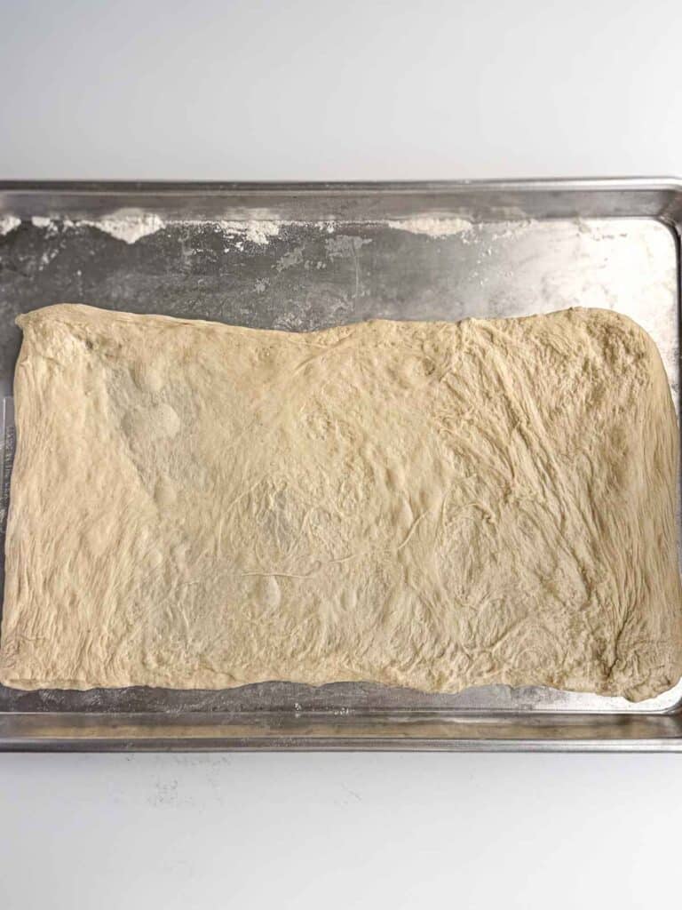 overhead view of pulled pizza dough formed into a rectangle on sheet pan
