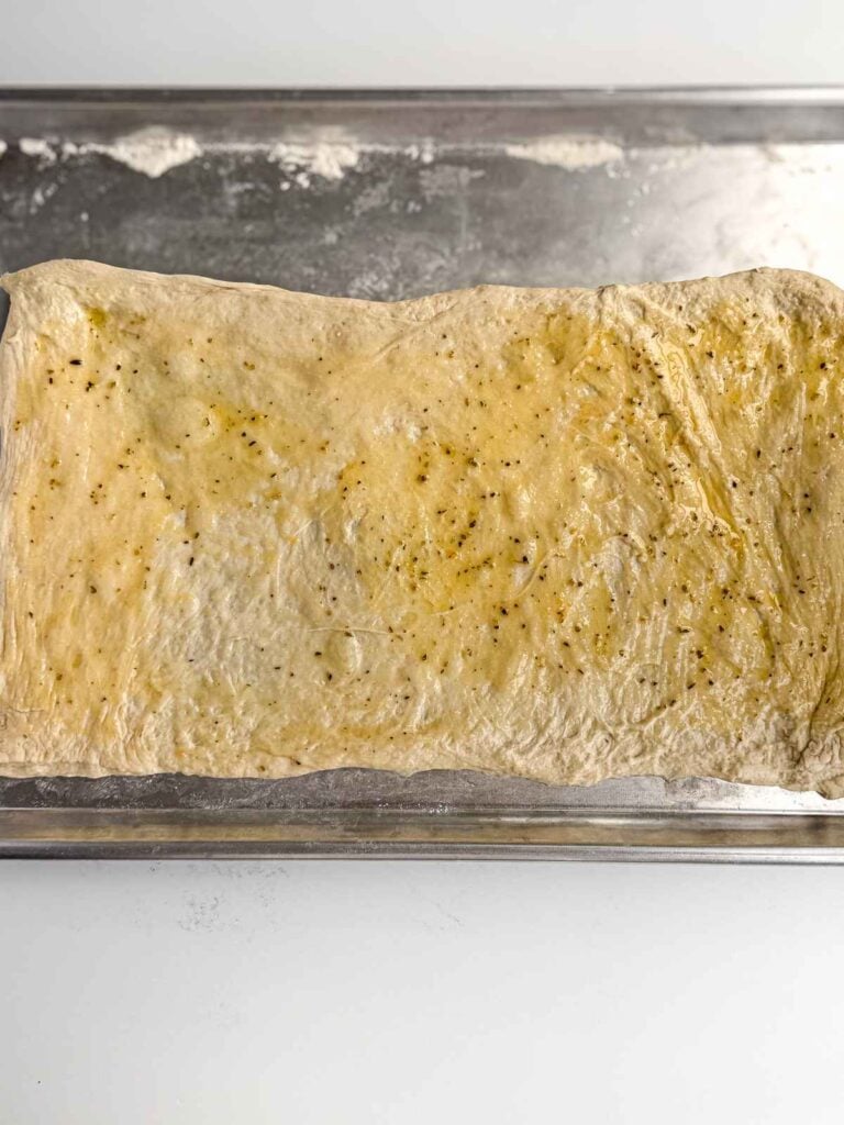 overhead view of pizza dough coated with garlic and onion powder butter